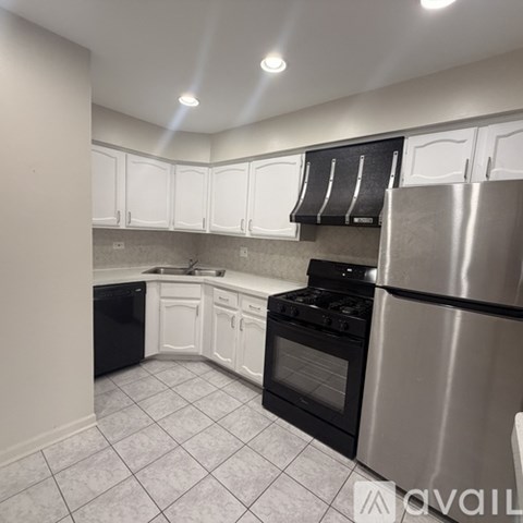 A kitchen with white cabinets and a stainless steel refrigerator.