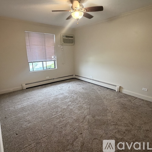 A room with a ceiling fan and a window with blinds.