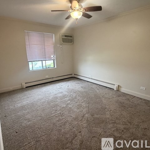 A room with a ceiling fan and a window with blinds.