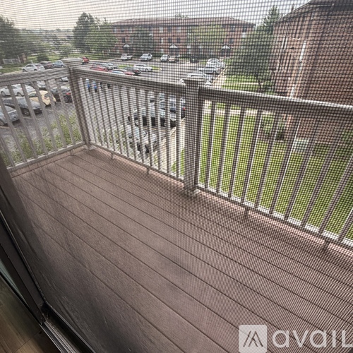 A balcony with a metal railing overlooks a parking lot.