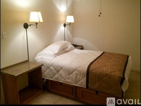 A bed with a white comforter and a brown blanket is in the image.
