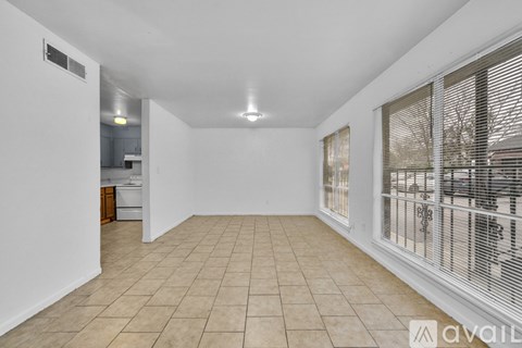 A spacious room with tiled flooring and a window with blinds.