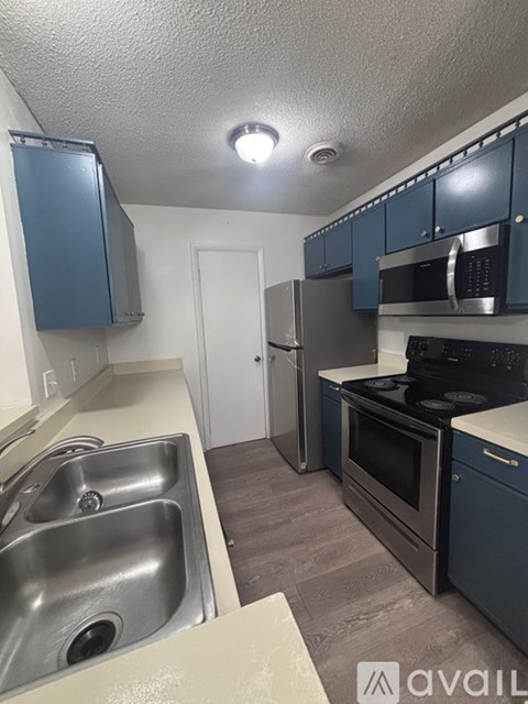 A kitchen with a sink, stove, and cabinets.