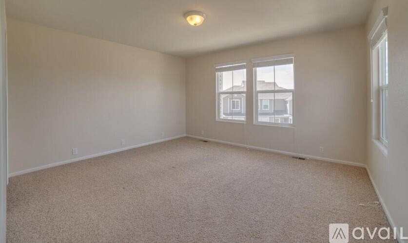 A room with a carpeted floor and a window overlooking a building.