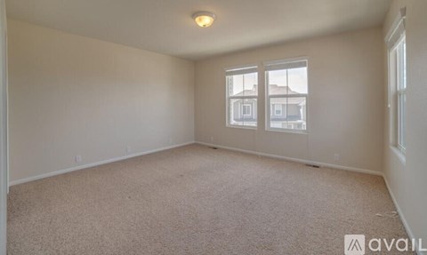 A room with a carpeted floor and a window overlooking a building.