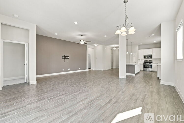 A spacious living room with a grey floor and a chandelier hanging from the ceiling.