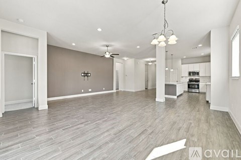 A spacious living room with a grey floor and a chandelier hanging from the ceiling.