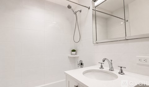 A white bathroom with a sink, mirror, and shower.
