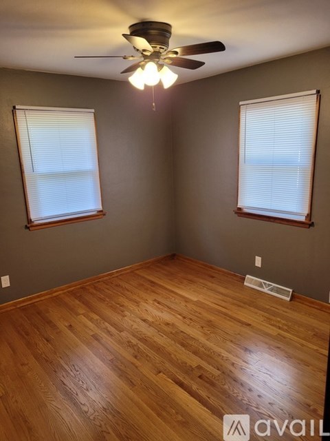 A room with wooden floors and two windows.