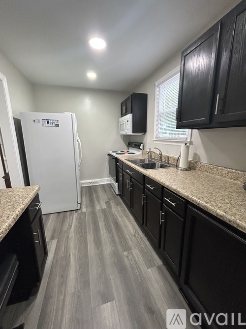 A kitchen with black cabinets and a white fridge.