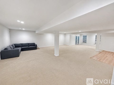 A spacious living room with a grey sofa and a carpeted floor.