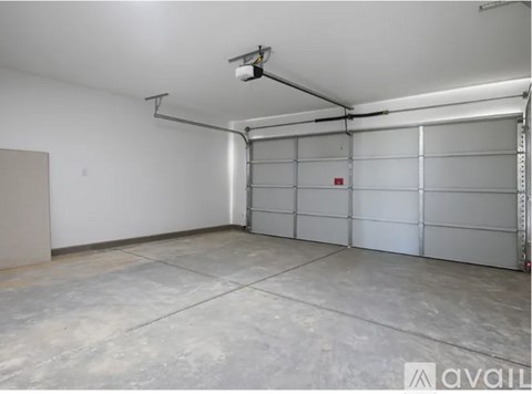 A spacious garage with a closed white door and a white ceiling with a light fixture.