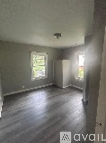 A room with wooden floors and two windows.