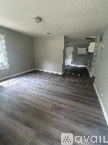 A room with a grey carpet and a bed in the background.