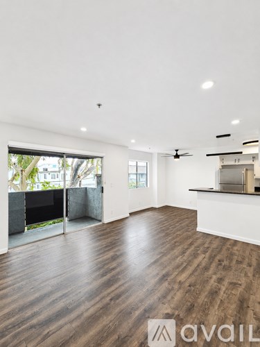 A spacious room with wooden flooring and a ceiling fan.