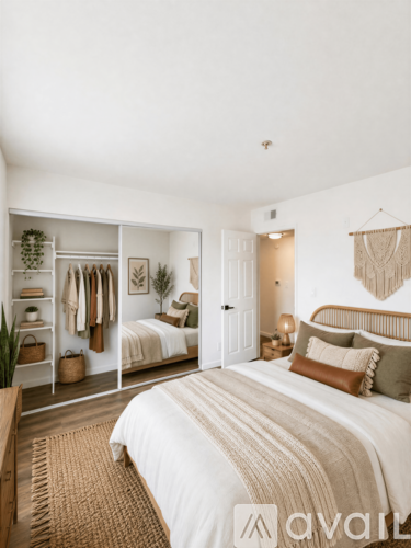 A bedroom with a large bed and a wardrobe with clothes hanging on it.