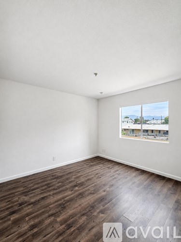 A room with wooden flooring and a window showing a view of buildings outside.