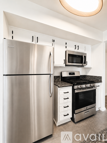 A kitchen with a stainless steel refrigerator and a black countertop.
