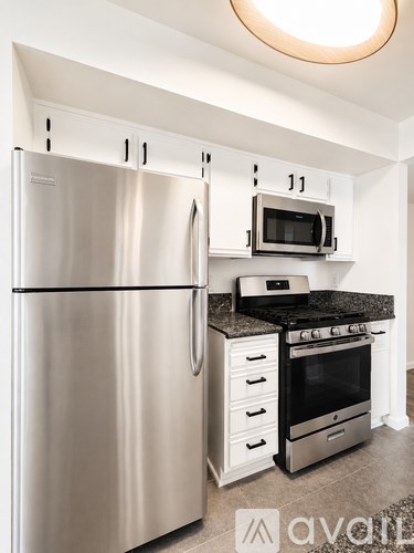 A kitchen with a stainless steel refrigerator and a black countertop.