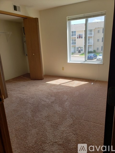 A room with a carpeted floor, a window, and a door.
