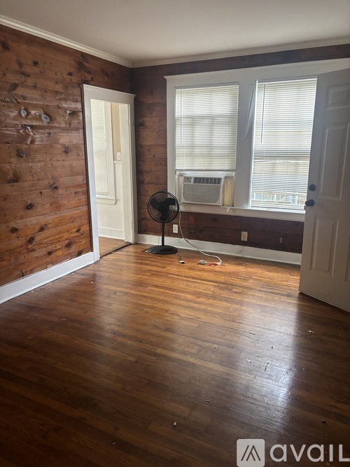 A room with wooden floors and a fan in the corner.