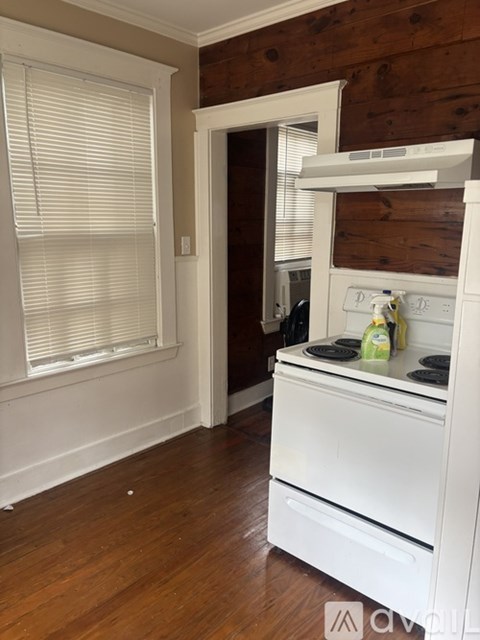 A white stove in a room with wooden walls.
