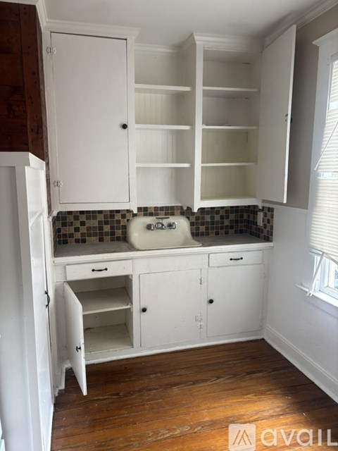A kitchen with white cabinets and a checkered backsplash.