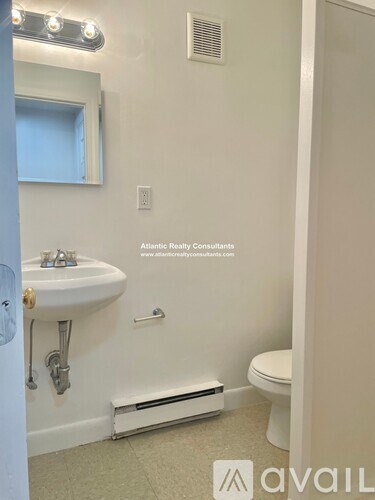 A bathroom with a toilet, sink, and mirror.