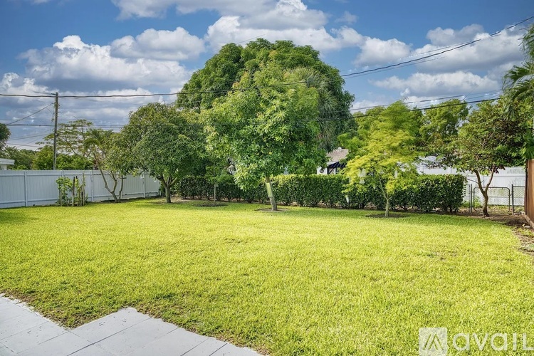 A backyard with a well-maintained lawn and a variety of trees.