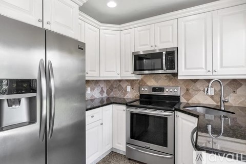 A kitchen with a stainless steel refrigerator, microwave, oven, and sink.
