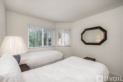 A bedroom with two beds and a mirror on the wall.
