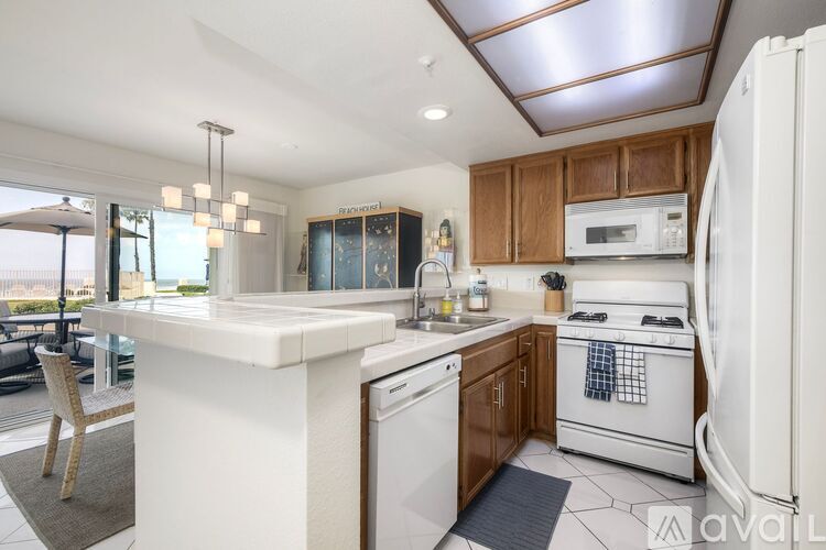 A modern kitchen with a white countertop and wooden cabinets.
