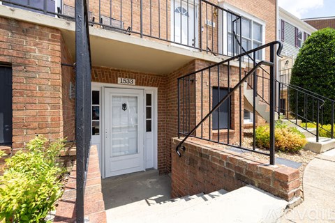 A white door is on the left side of a brick wall.