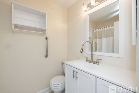 A white bathroom with a toilet, sink, and mirror.