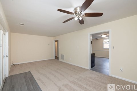 A spacious room with a ceiling fan and a rug on the floor.