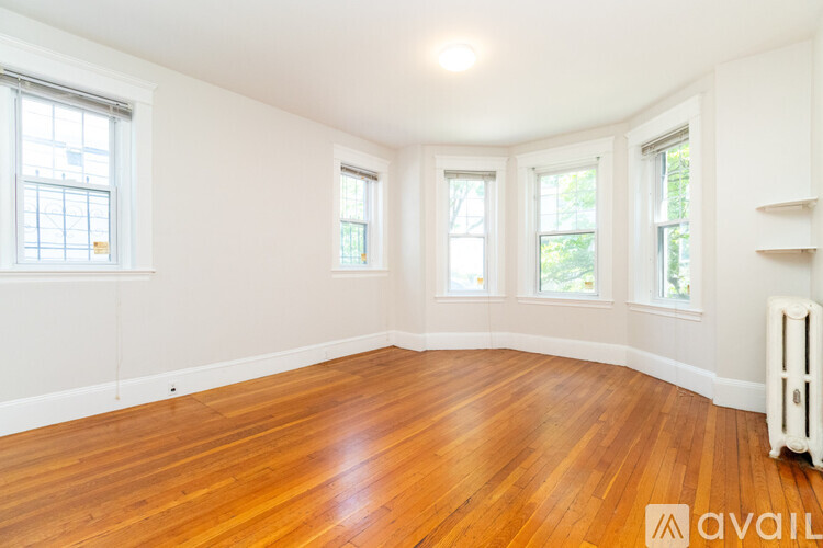 A room with wooden floors and three windows.