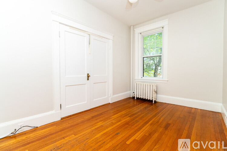 A room with wooden floors and a window with a view of trees outside.