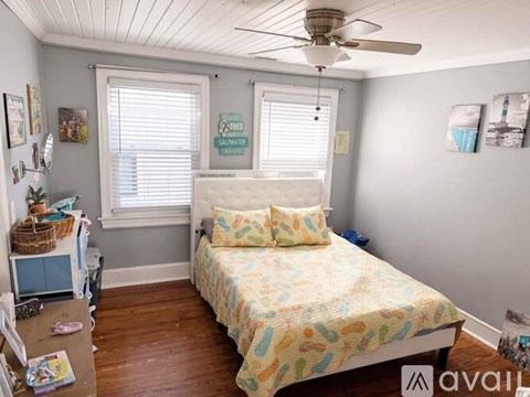 A bedroom with a bed, a fan, and a window.