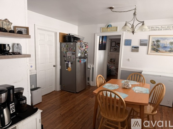 A kitchen with a fridge, table and chairs.