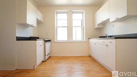 A kitchen with white cabinets and black countertops.