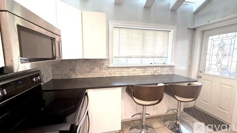 A kitchen with a black oven and microwave, a black countertop, and white cabinets.