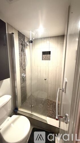 A bathroom with a toilet, a glass shower stall, and a glass door.