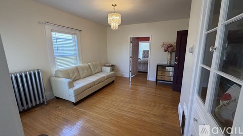 A living room with a white couch and wooden floors.