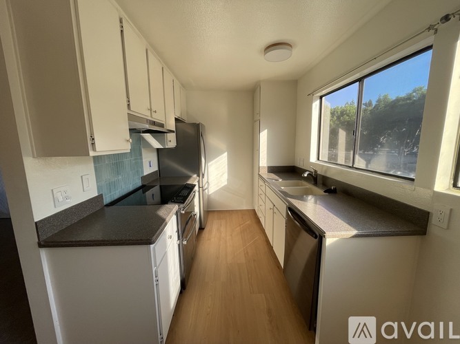A kitchen with white cabinets and a black countertop.