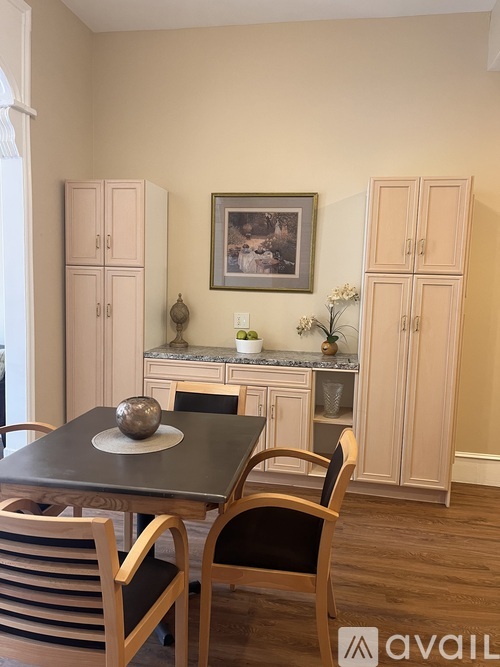 A dining room with a table, chairs and cabinets.