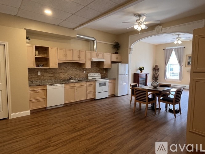 A kitchen with wooden floors and a dining table with chairs.