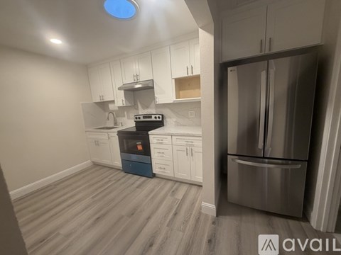 A kitchen with a refrigerator, stove, and cabinets.
