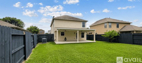 A house with a fenced backyard and a tree.