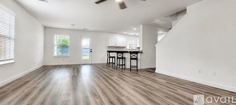 A spacious room with wooden floors and a bar area.