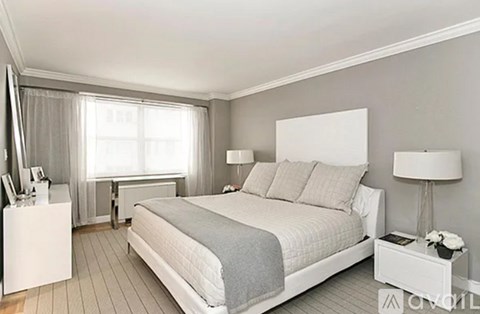 A bedroom with a large bed, nightstand, and window.